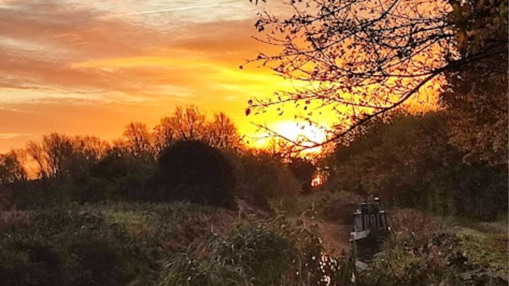 Slow living on a narrowboat with autumn leaves turning orange and a sunset